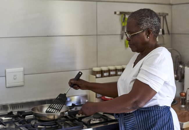 Senior woman cooking at gas stove in kitchen senior-woman-cooking-at-gas-stove-in-kitchen