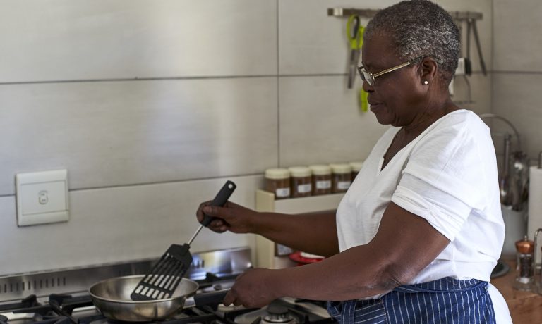Senior woman cooking at gas stove in kitchen senior-woman-cooking-at-gas-stove-in-kitchen