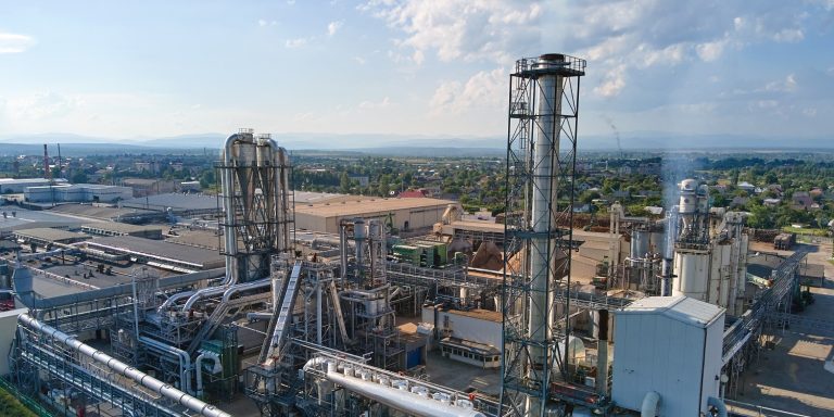 Aerial view of oil and gas refining petrochemical factory with tall refinery plant manufacture structure.