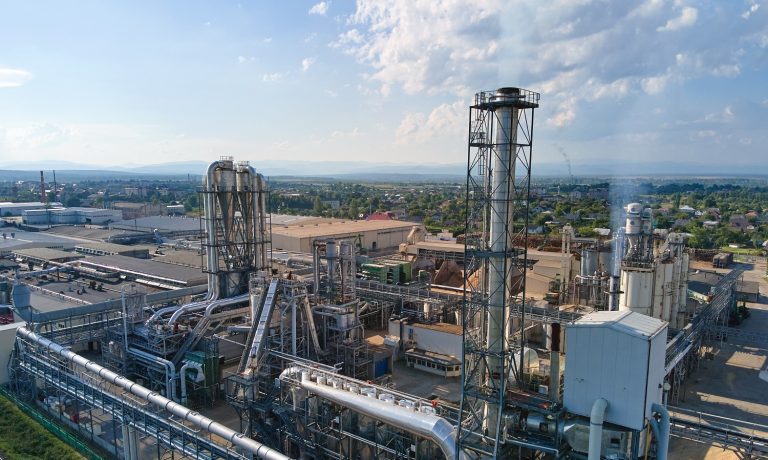 Aerial view of oil and gas refining petrochemical factory with tall refinery plant manufacture structure.