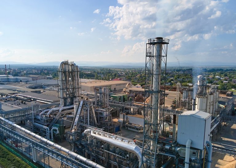 Aerial view of oil and gas refining petrochemical factory with tall refinery plant manufacture structure.