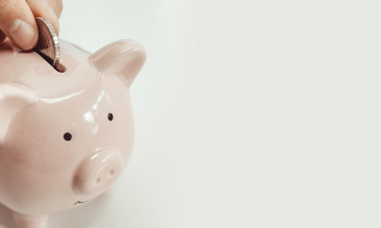 Close up of woman putting a coin inside piggy bank as investment. save money concept Gas natural vehicular