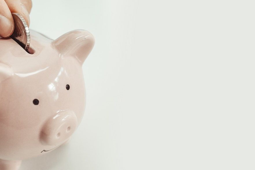 Close up of woman putting a coin inside piggy bank as investment. save money concept Gas natural vehicular
