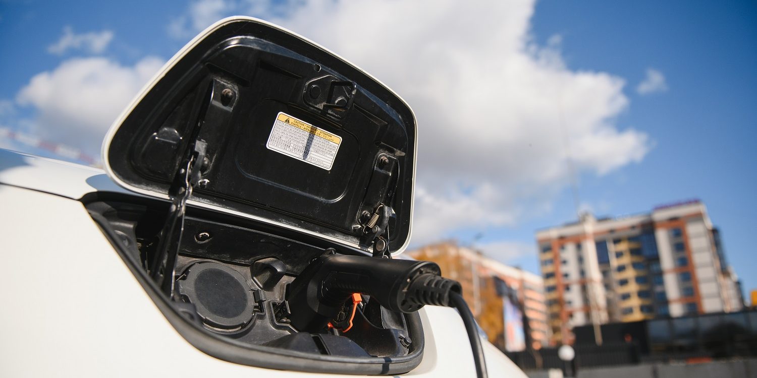 Charging modern electric car battery on the street which are the future of the Automobile, Close up of power supply plugged into an electric car being charged for hybrid . New era of vehicle fuel.