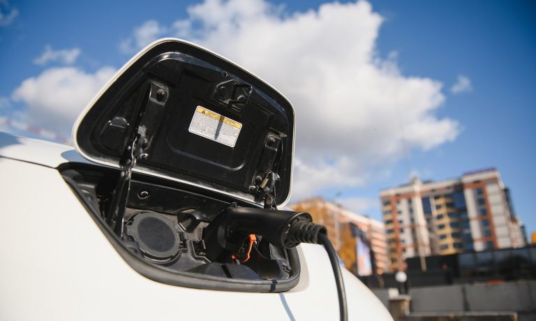 Charging modern electric car battery on the street which are the future of the Automobile, Close up of power supply plugged into an electric car being charged for hybrid . New era of vehicle fuel.