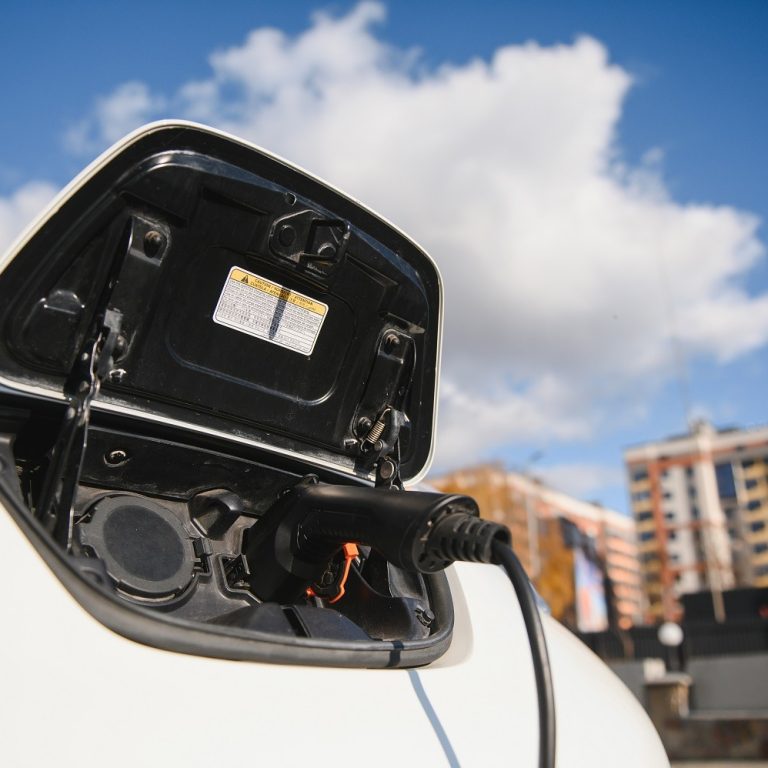 Charging modern electric car battery on the street which are the future of the Automobile, Close up of power supply plugged into an electric car being charged for hybrid . New era of vehicle fuel.
