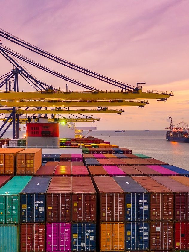 Container ship loading and unloading in deep sea port at sunset,