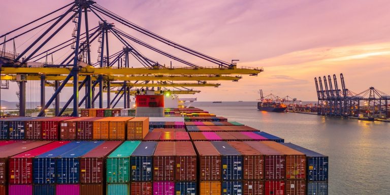 Container ship loading and unloading in deep sea port at sunset,