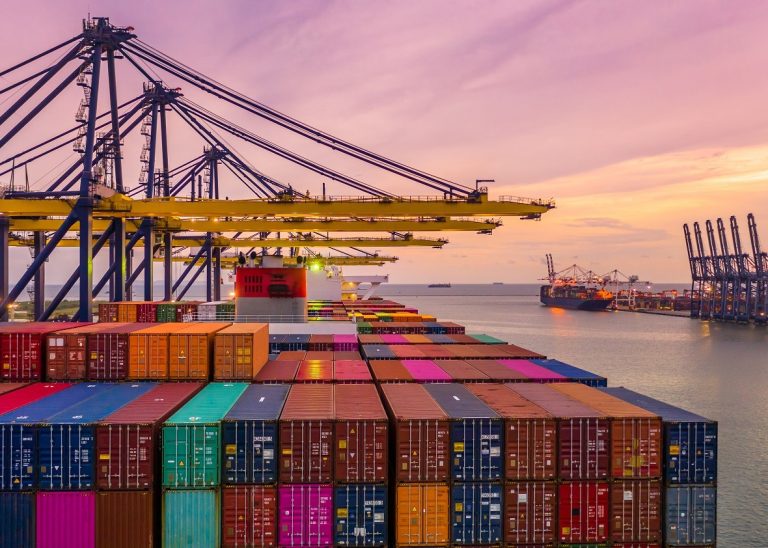 Container ship loading and unloading in deep sea port at sunset,