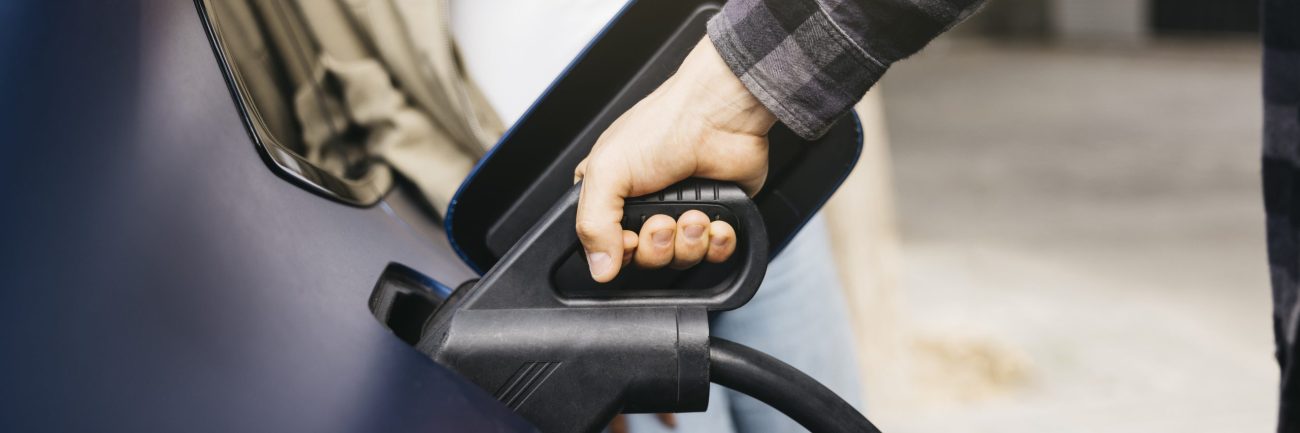 Couple charging electric car together at outdoor charging statio