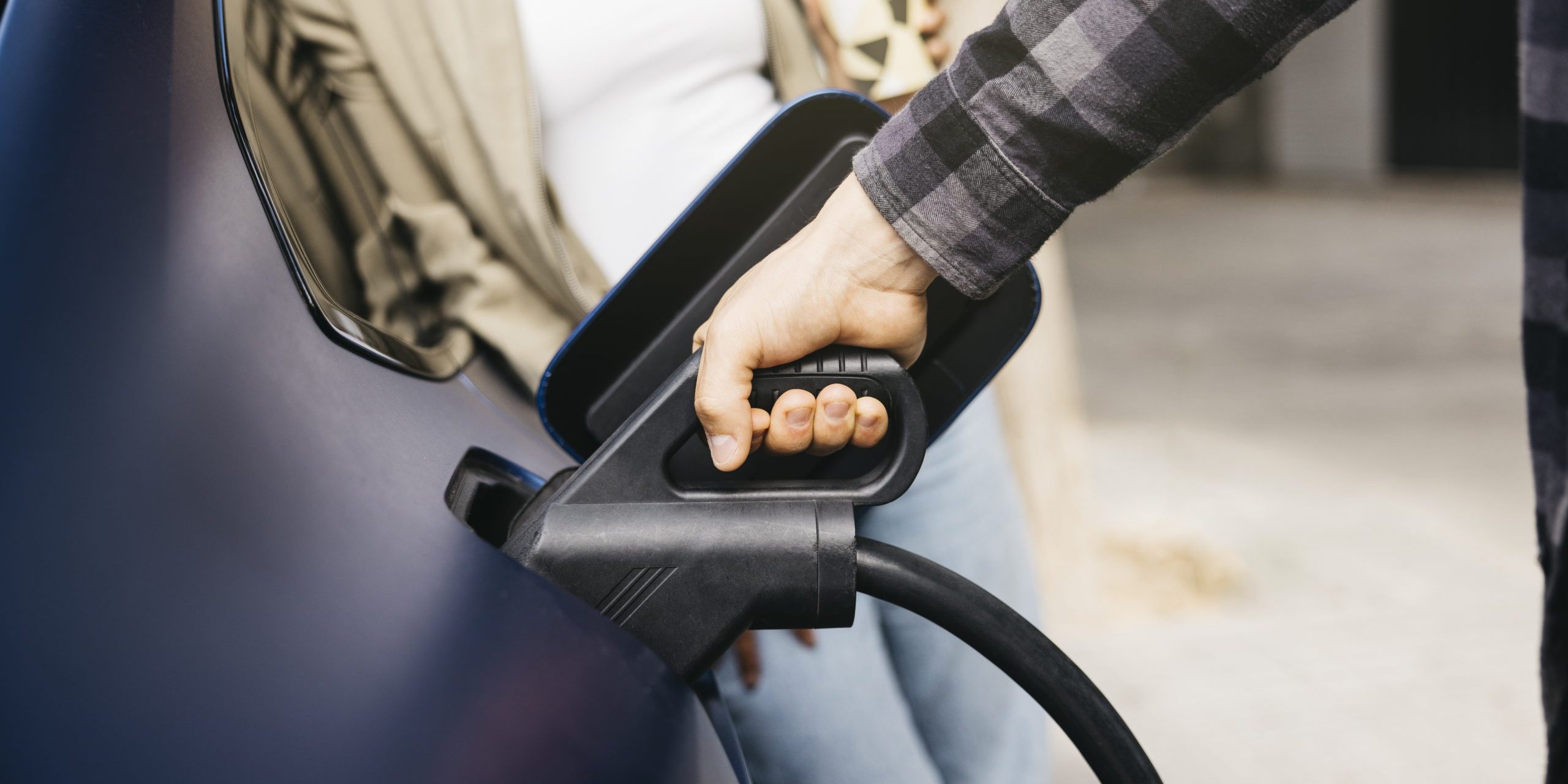 Couple charging electric car together at outdoor charging statio