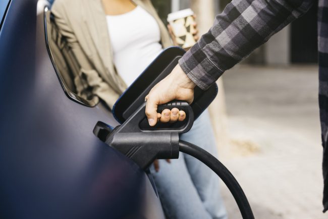 Couple charging electric car together at outdoor charging statio