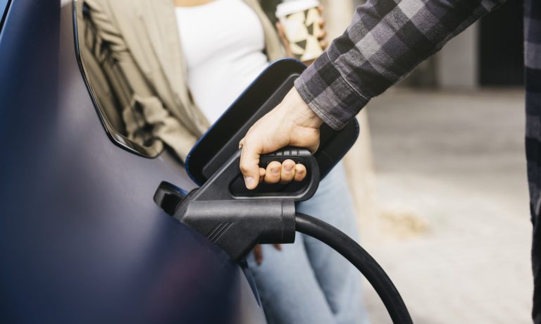 Couple charging electric car together at outdoor charging statio