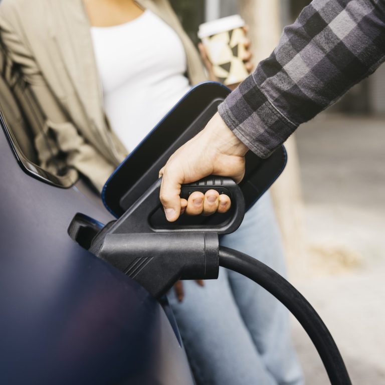Couple charging electric car together at outdoor charging statio
