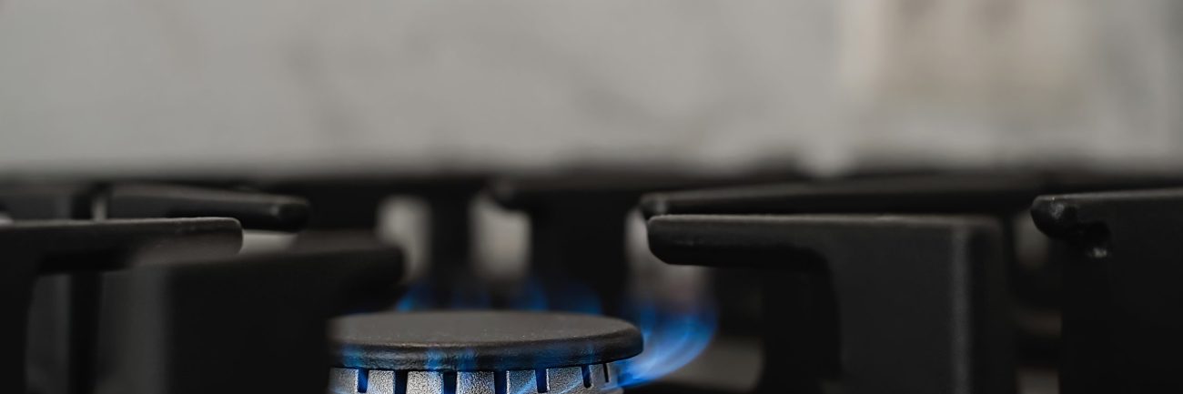 Modern kitchen stove, natural gas burns with a blue flame. Household gas consumption. Close-up, selective focus