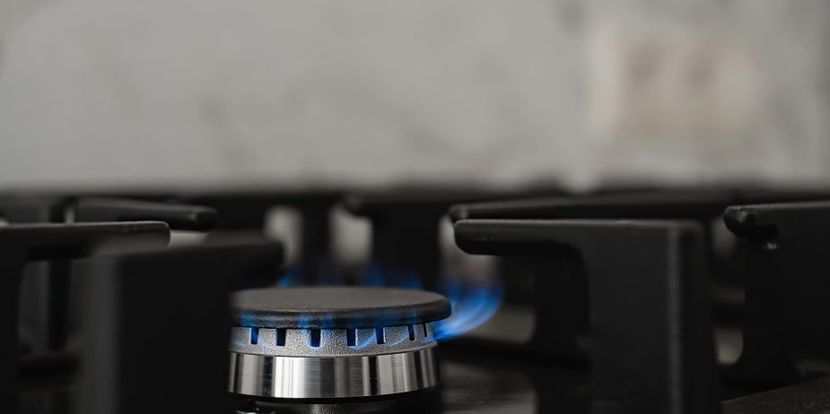 Modern kitchen stove, natural gas burns with a blue flame. Household gas consumption. Close-up, selective focus