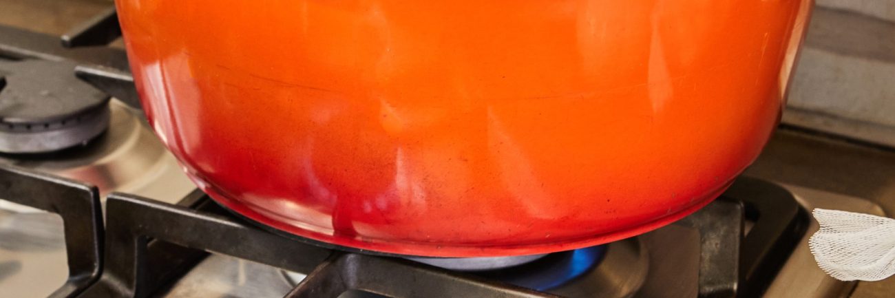 Stuffed zucchini and peppers are cooked in covered pan on gas stove