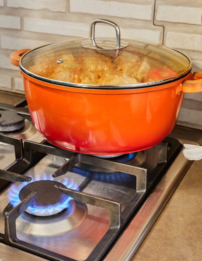 Stuffed zucchini and peppers are cooked in covered pan on gas stove