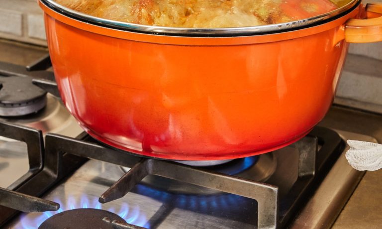 Stuffed zucchini and peppers are cooked in covered pan on gas stove
