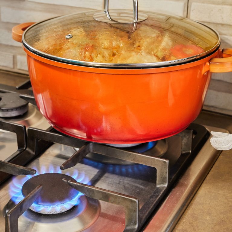 Stuffed zucchini and peppers are cooked in covered pan on gas stove