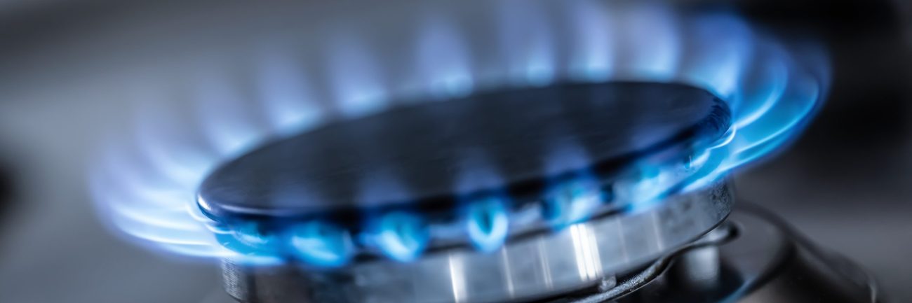 The gas burner burns with the blue flame of a propane butane stove in a home kitchen or hotel restaurant.