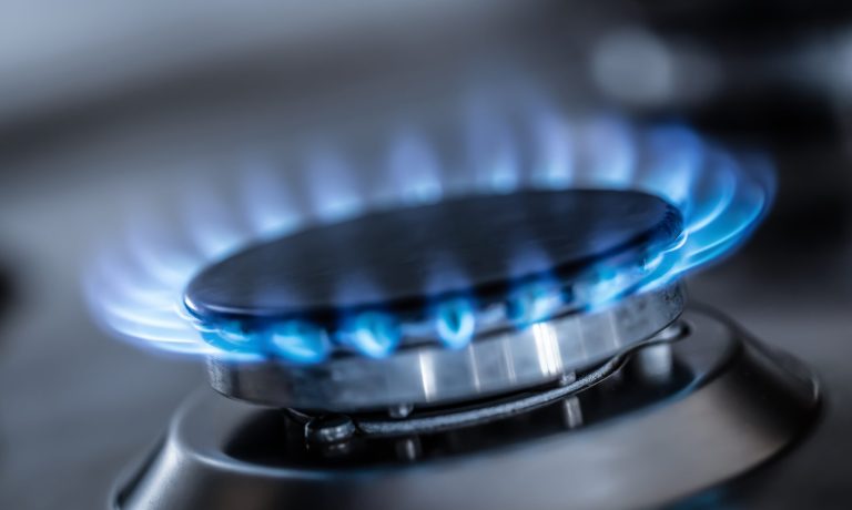 The gas burner burns with the blue flame of a propane butane stove in a home kitchen or hotel restaurant.