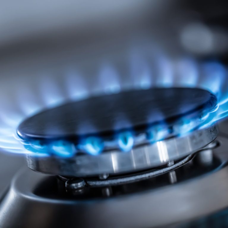 The gas burner burns with the blue flame of a propane butane stove in a home kitchen or hotel restaurant.