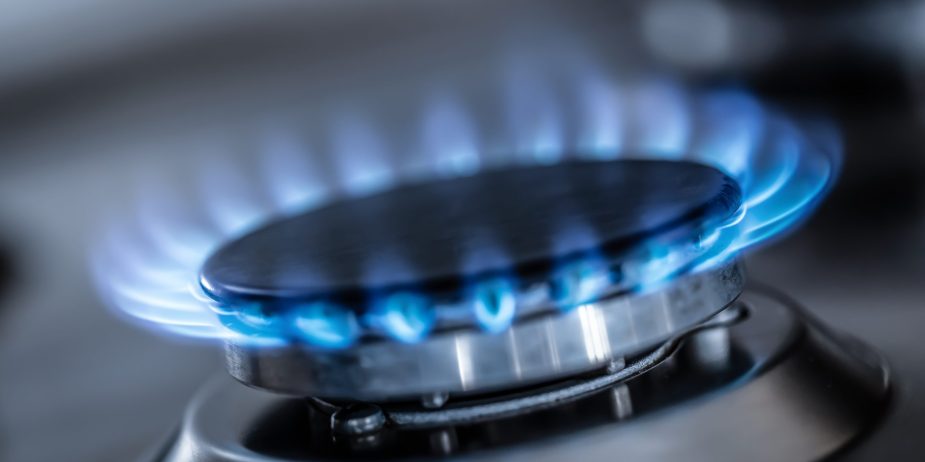 The gas burner burns with the blue flame of a propane butane stove in a home kitchen or hotel restaurant.