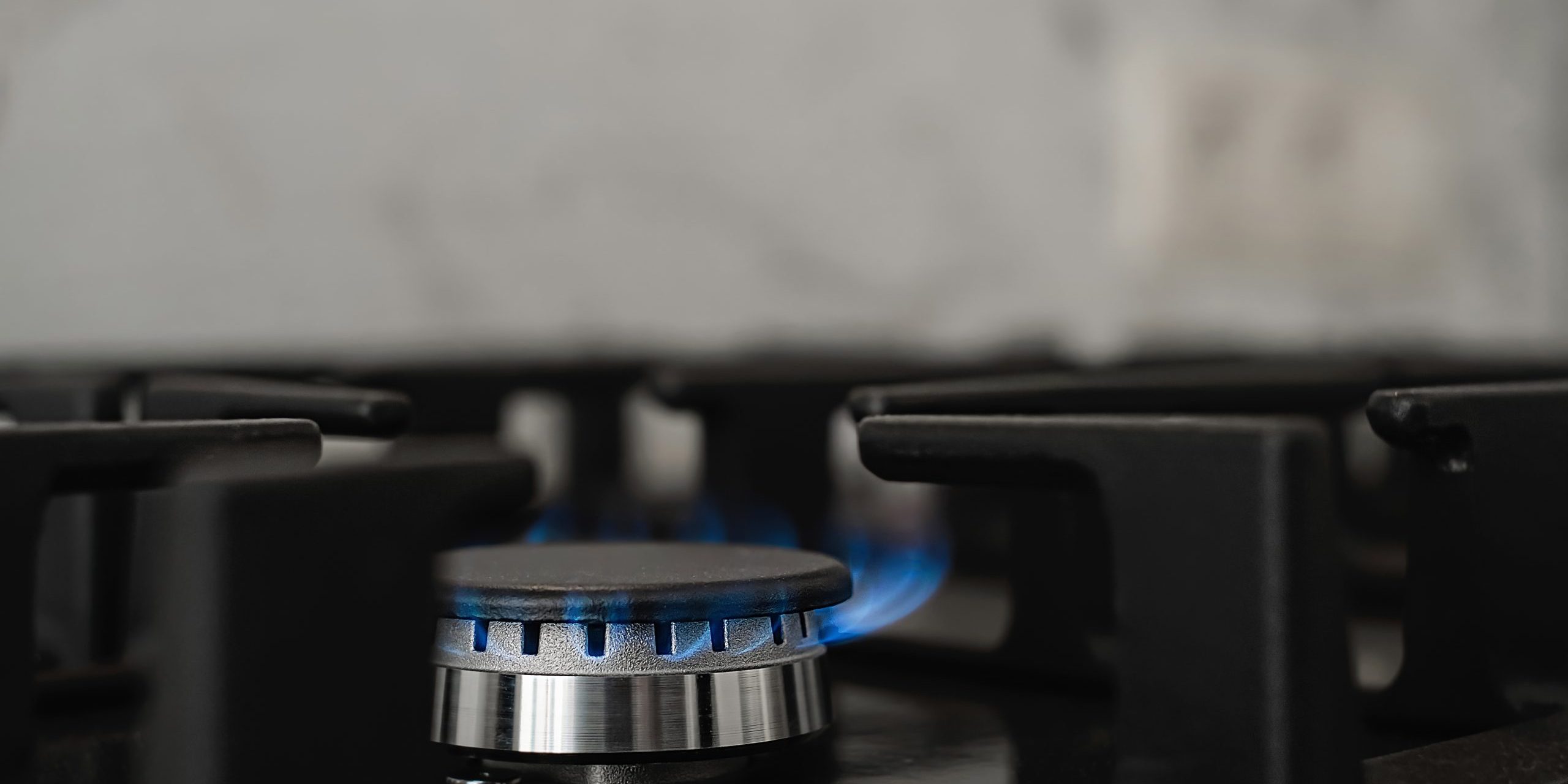 Modern kitchen stove, natural gas burns with a blue flame. Household gas consumption. Close-up, selective focus