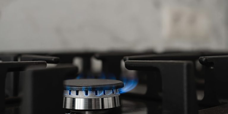 Modern kitchen stove, natural gas burns with a blue flame. Household gas consumption. Close-up, selective focus