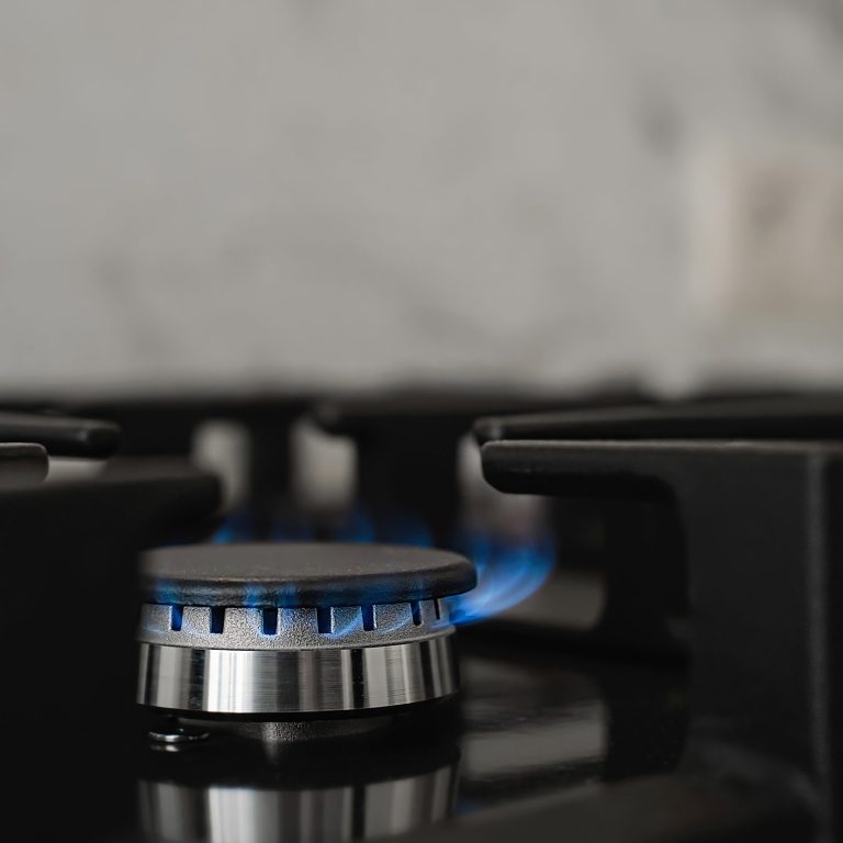 Modern kitchen stove, natural gas burns with a blue flame. Household gas consumption. Close-up, selective focus