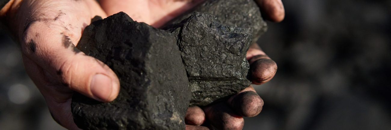 poor middle-aged man holding the hands of stone coal for sale to provide food for his family