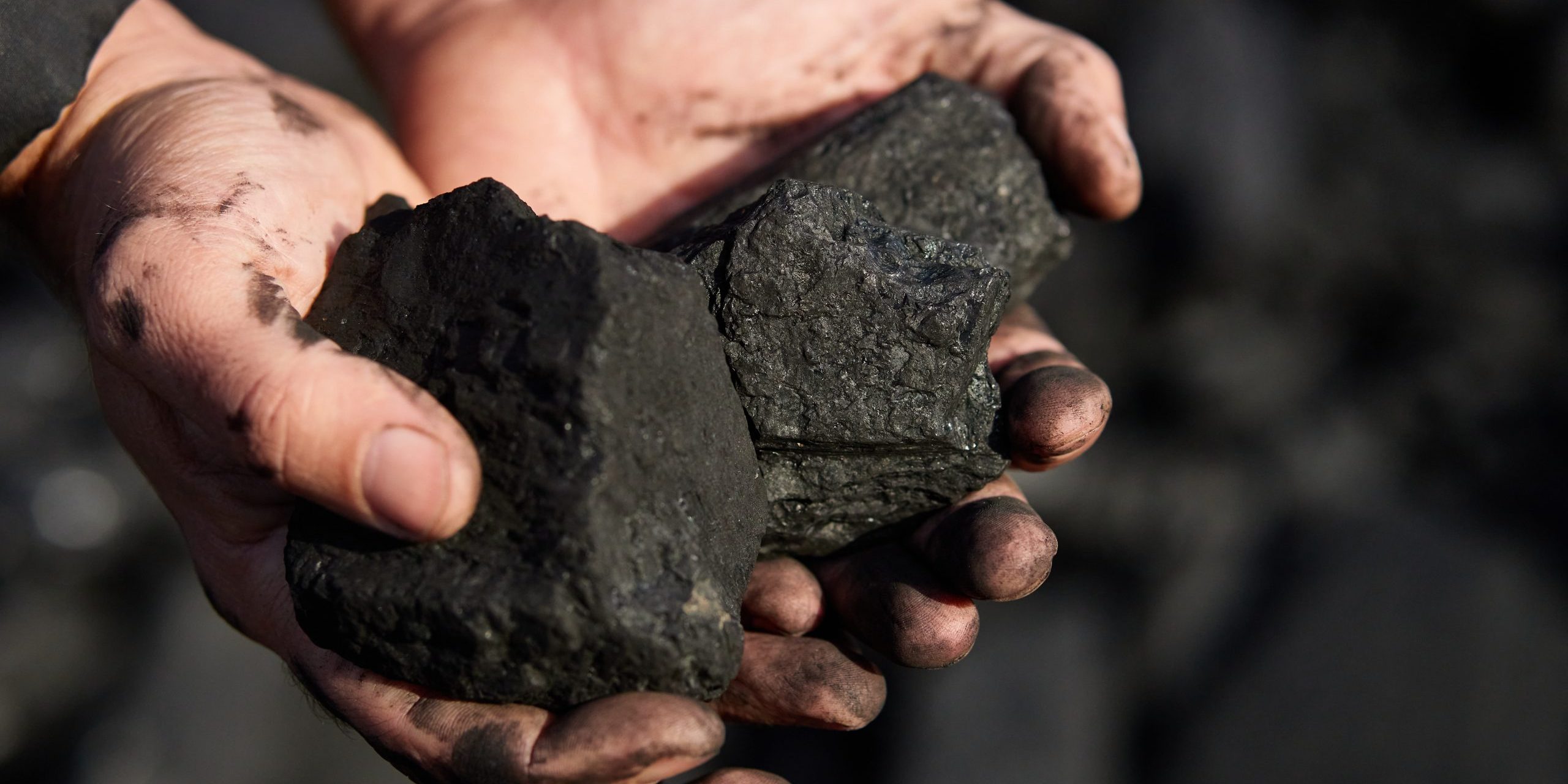 poor middle-aged man holding the hands of stone coal for sale to provide food for his family