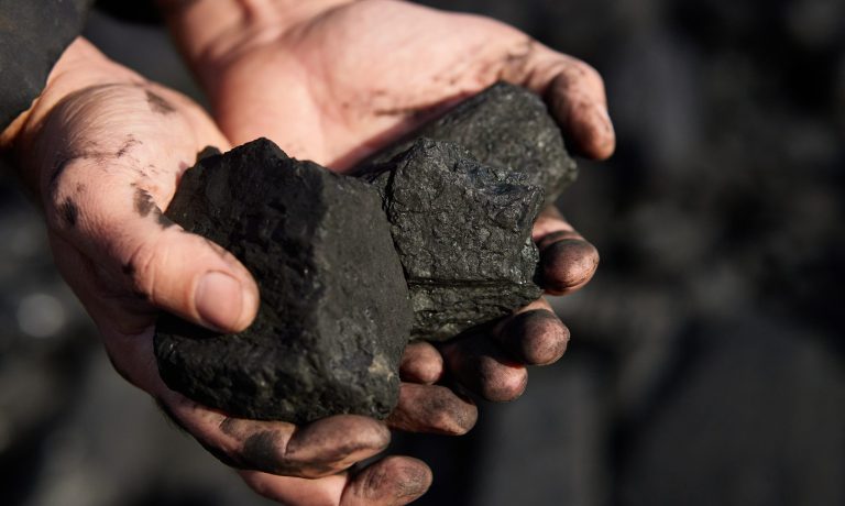 poor middle-aged man holding the hands of stone coal for sale to provide food for his family