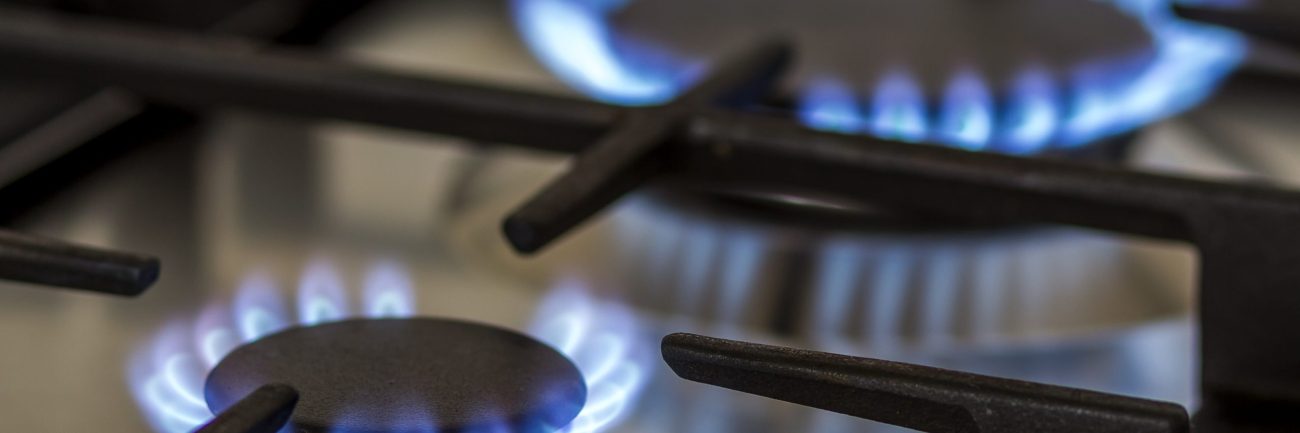 Natural gas burning on kitchen gas stove in the dark. Panel from steel with a gas ring burner on a black background, close-up shooting