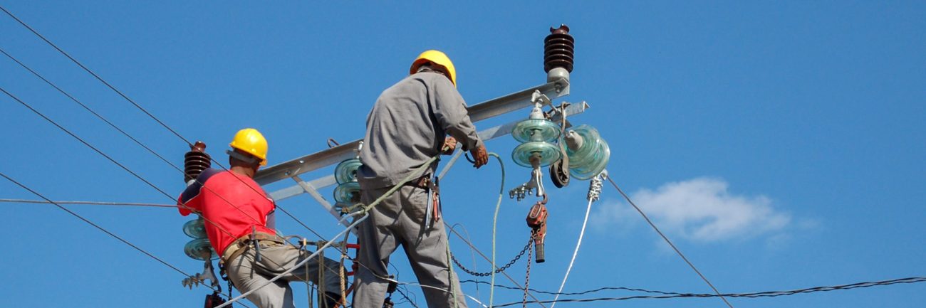 Low angle shot of electric linemen working on pole