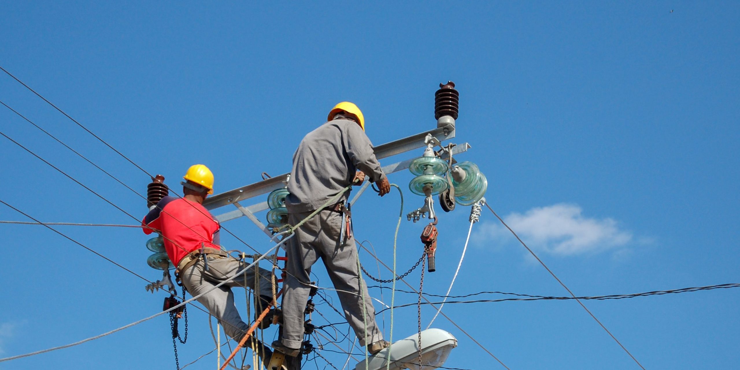 Low angle shot of electric linemen working on pole