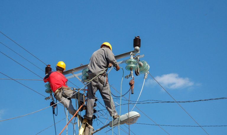 Low angle shot of electric linemen working on pole