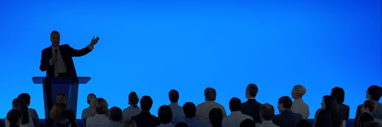 Corporate businessman giving a presentation to a large audience