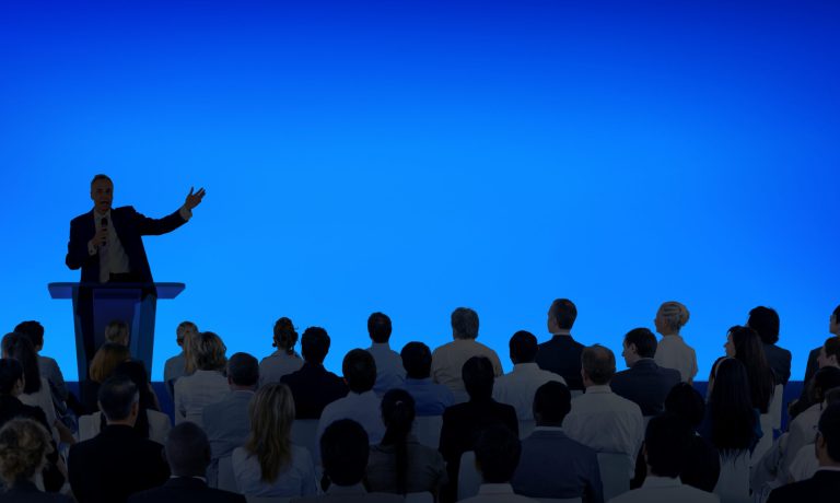 Corporate businessman giving a presentation to a large audience