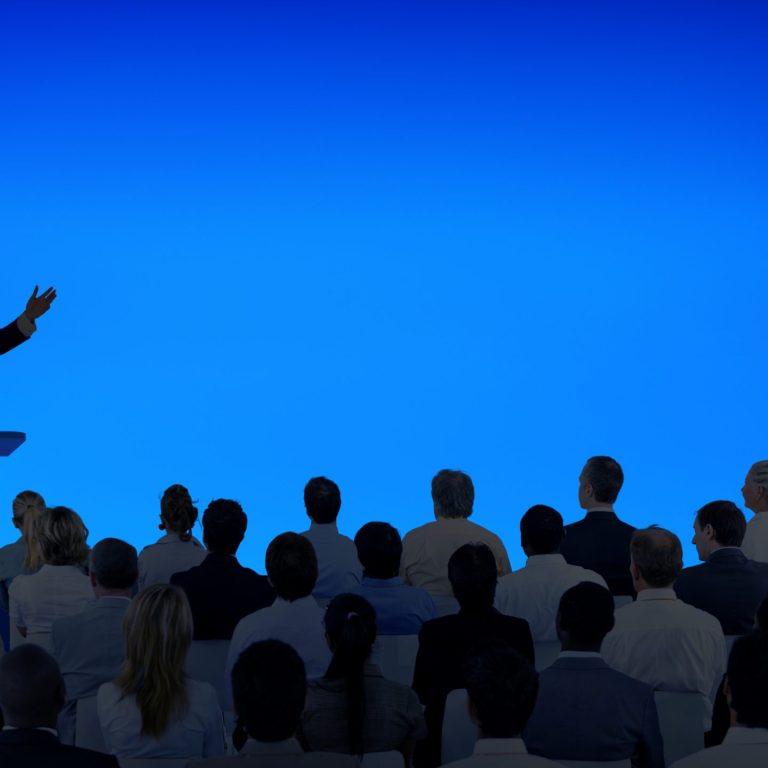 Corporate businessman giving a presentation to a large audience