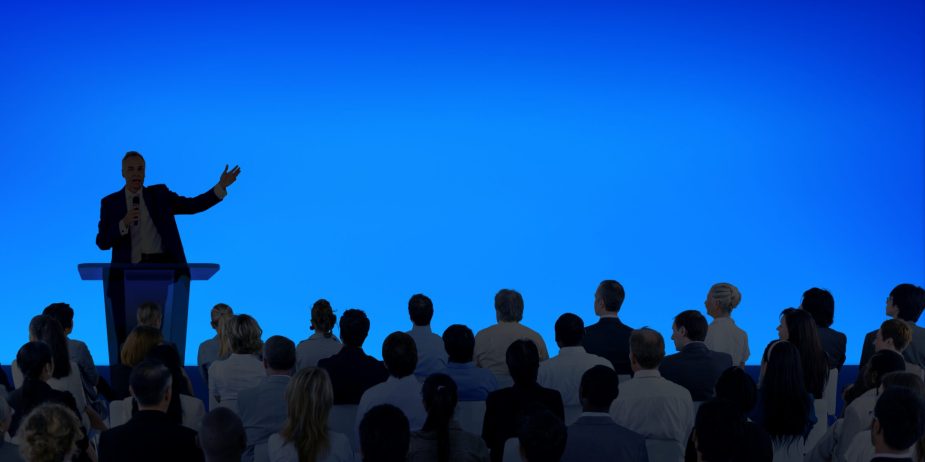 Corporate businessman giving a presentation to a large audience