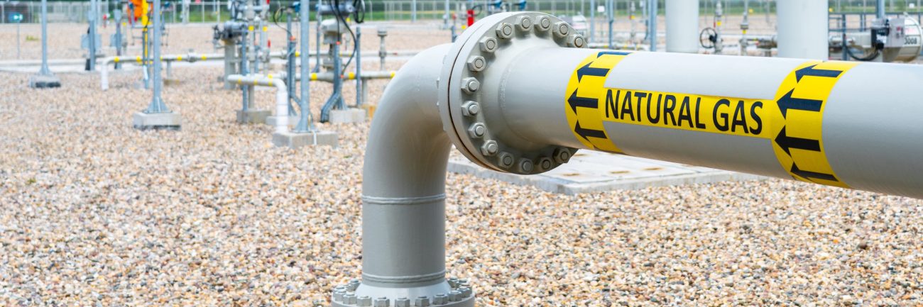 Turn and underground transition of high pressure pipe indicating natural gas and flow direction