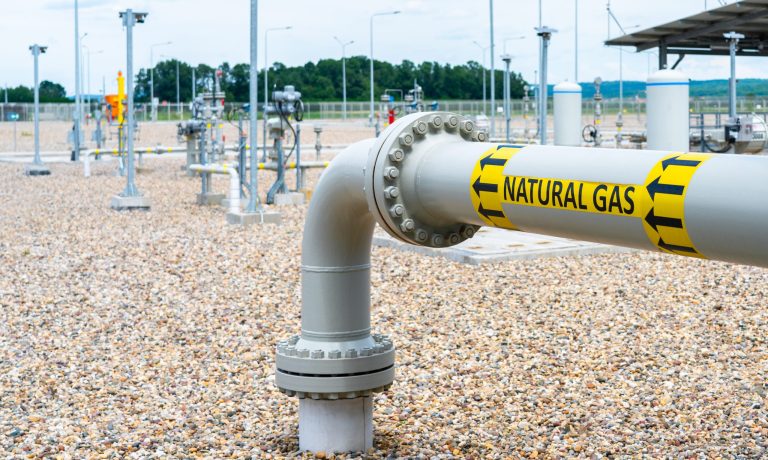 Turn and underground transition of high pressure pipe indicating natural gas and flow direction