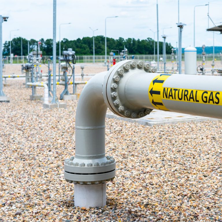 Turn and underground transition of high pressure pipe indicating natural gas and flow direction
