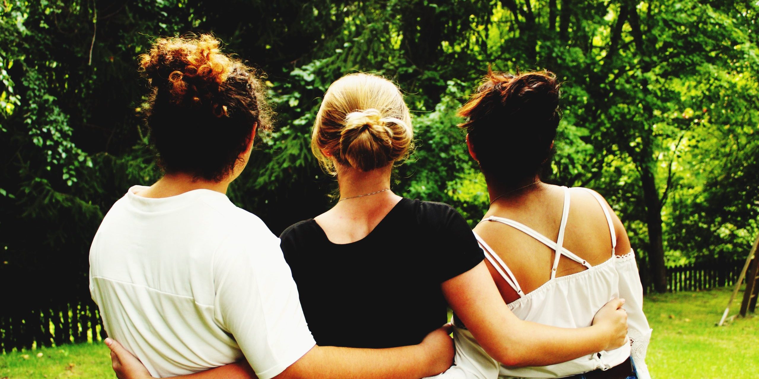 vista-trasera-de-amigos-de-pie-en-el-parque