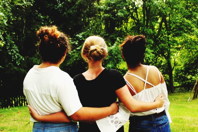 vista-trasera-de-amigos-de-pie-en-el-parque