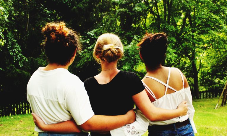 vista-trasera-de-amigos-de-pie-en-el-parque