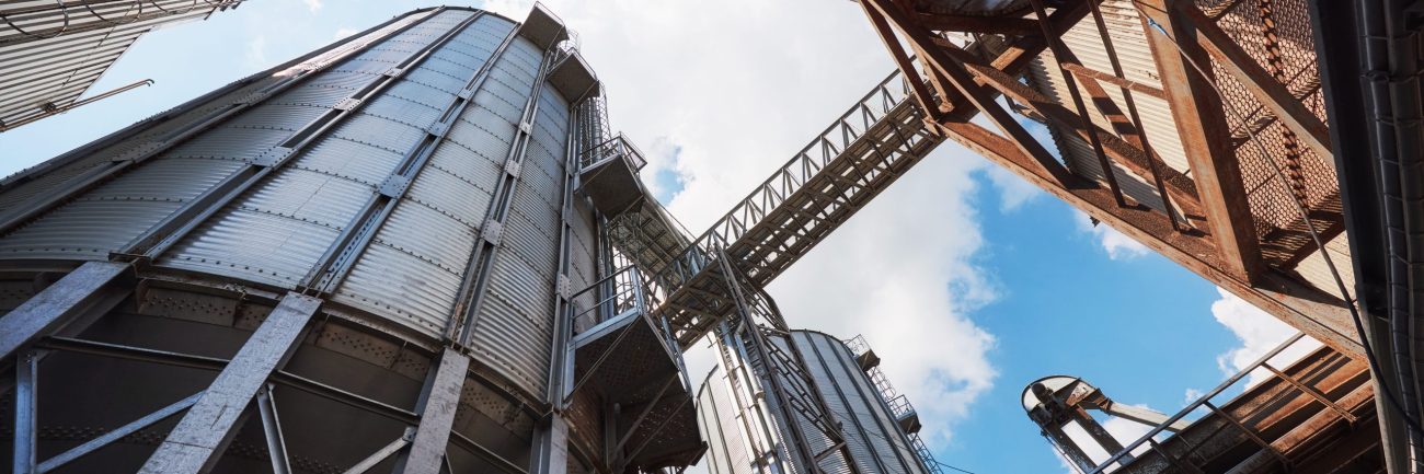 Agricultural Silos. Building Exterior. Storage and drying of grains, wheat, corn, soy, sunflower against the blue sky with white clouds