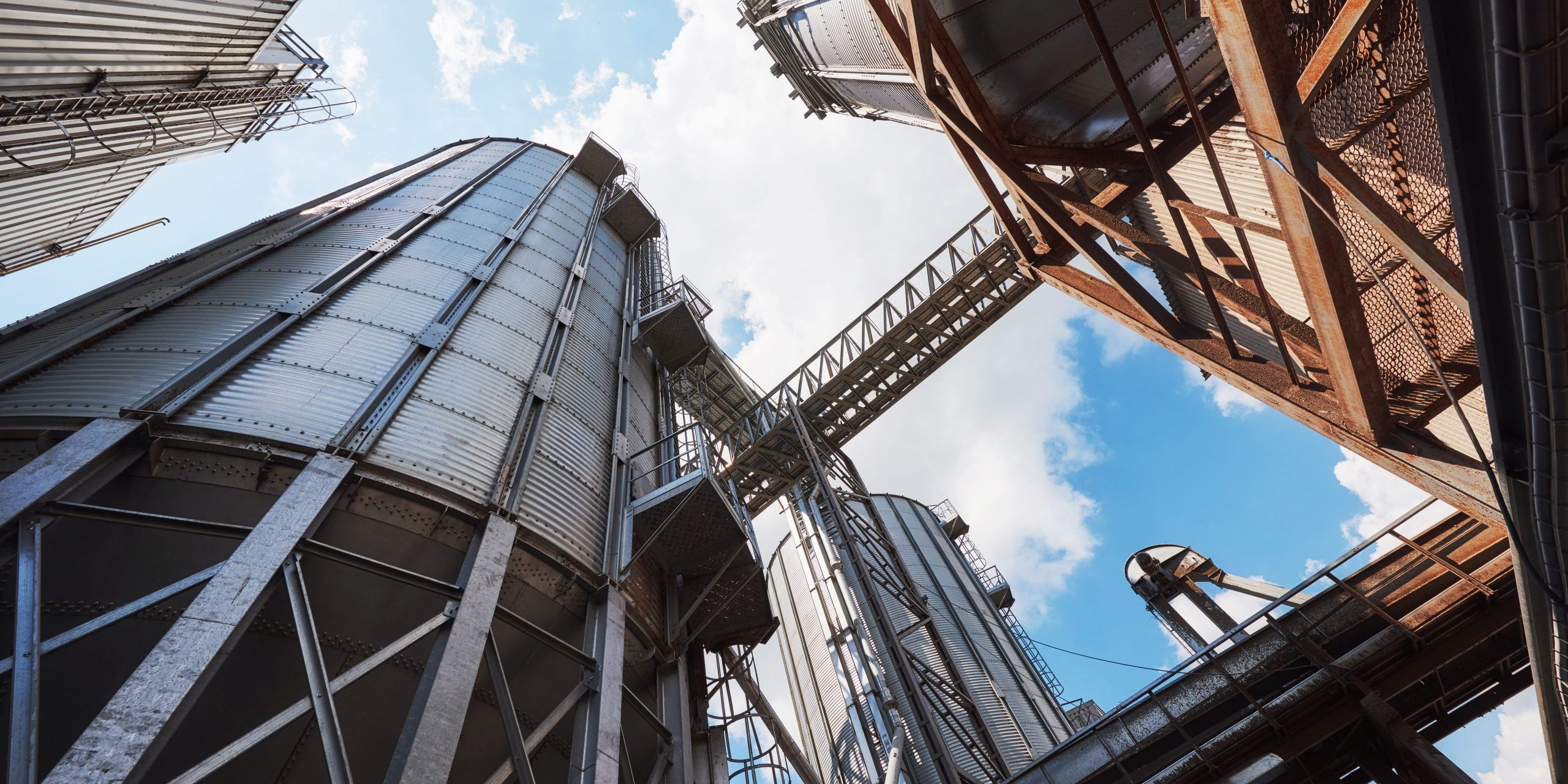 Agricultural Silos. Building Exterior. Storage and drying of grains, wheat, corn, soy, sunflower against the blue sky with white clouds